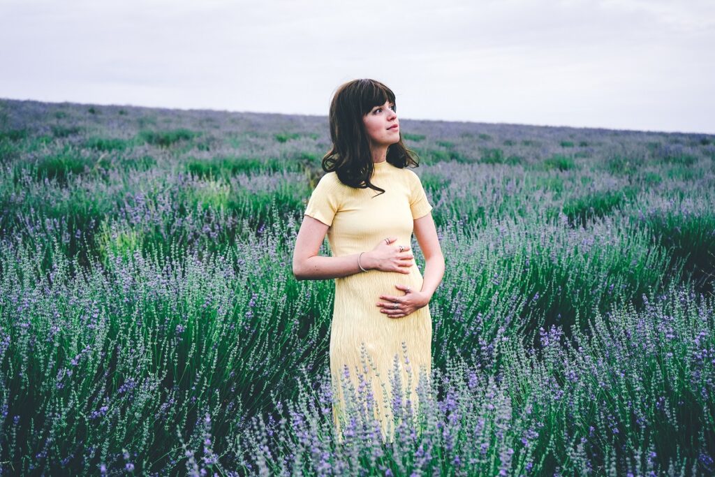 Kobieta w drugim miesiącu ciąży stoi w polu